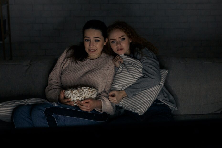 Girls watching horror movie on tv sitting on couch