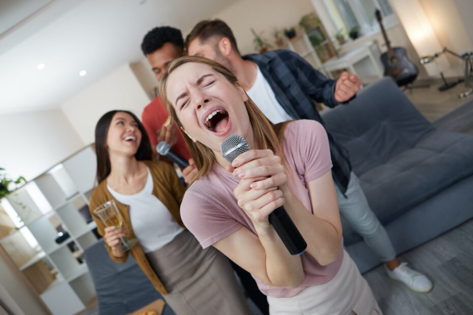 Karaoke singer. Beautiful young girl holding microphone and singing while playing karaoke with best